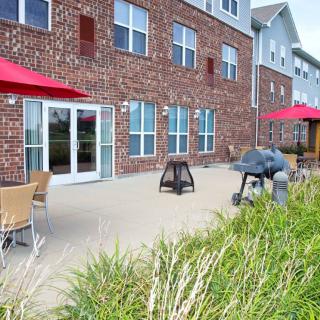 A patio area with outdoor seating and red umbrellas in front of a brick building.
