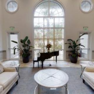 A luxurious lobby featuring a grand piano and elegant seating area with large windows.