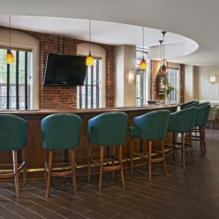 A modern bar interior with teal seating and pendant lighting.