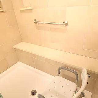 Accessible bathroom with a shower seat and grab bar.