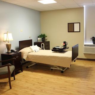 A well-lit patient room equipped with essential furniture, including a bed and a bedside lamp.