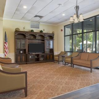 A spacious waiting room with seating, a television, and large windows letting in natural light.