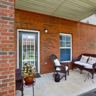 A cozy outdoor patio with wicker furniture and brick walls.