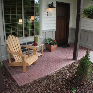 A cozy front porch with a wooden chair and potted plants.