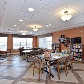 A quiet library reading room with tables, chairs, and bookshelves.