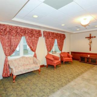A cozy living room with elegant curtains, seating and a wall-mounted cross.