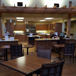 A spacious dining area featuring wooden furniture and a modern kitchen setup.
