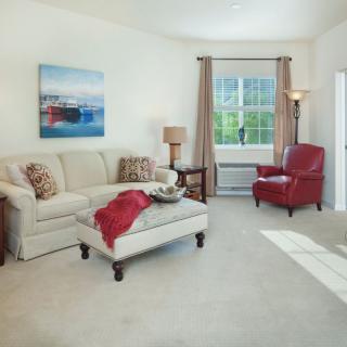 A cozy living room with a comfortable sofa and a red armchair, accented by a large window and stylish decor.