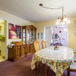 A cozy dining room with a floral tablecloth, ornate wooden furniture, and decorative artwork.