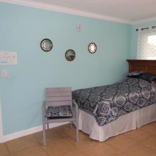 A cozy bedroom with an aqua-colored wall, a bed with patterned bedding, and a chair next to it.