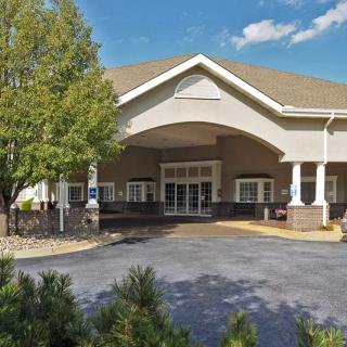 A building entrance with a covered driveway and surrounding trees.