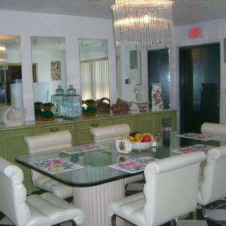 A stylish dining room featuring a glass-top table, cushioned chairs, and an elegant chandelier.