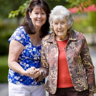 Two women smiling and holding hands outdoors.