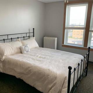 A cozy bedroom with a neatly made bed, brightened by natural light from a large window.
