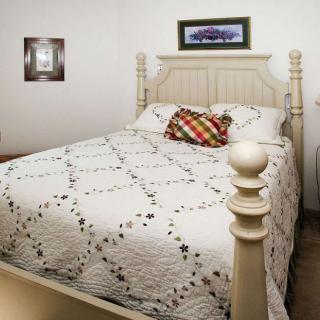 A cozy bedroom with a neatly made bed featuring a patterned quilt and decorative pillows.