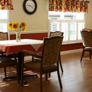 A cozy dining area with a table, chairs, and sunflowers near large windows.