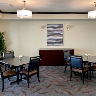A modern dining area featuring tables and chairs, complemented by decorative artwork and indoor plants.