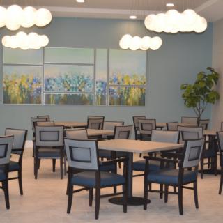 A modern dining area with multiple tables and chairs under stylish lighting fixtures.