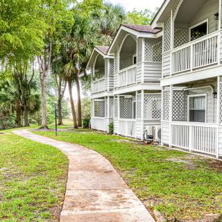 A scenic view of a residential building with a winding pathway surrounded by lush greenery and trees.