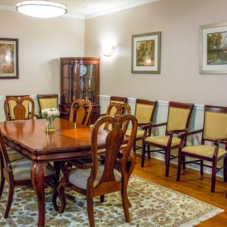 A traditional dining room featuring a wooden table, matching chairs, and a decorative cabinet.
