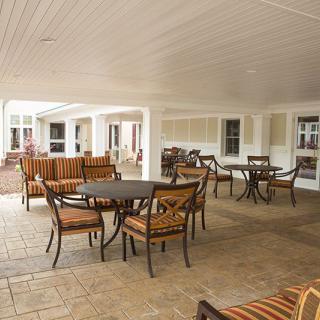 A spacious outdoor patio with several tables and chairs under a covered area.