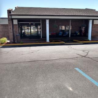 A view of a commercial building entrance with a parking lot in front.