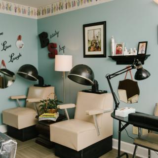 A cozy salon interior with chairs, hair dryers, and decorative wall art.