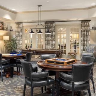 A luxurious game room featuring round tables, comfortable seating, and elegant decor.