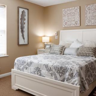 A cozy bedroom with tasteful decor, featuring a large bed, patterned bedding, and decorative artwork on the walls.