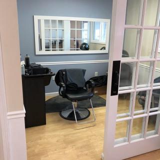 A cozy hair salon with a modern design featuring a styling chair and mirror.