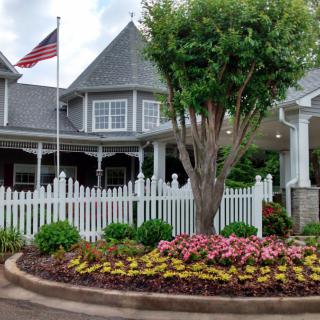 A charming house with a vibrant garden and an American flag.
