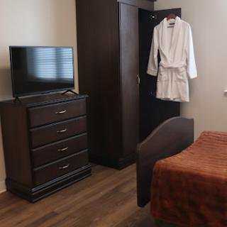 A cozy hotel room featuring a dresser, television, and a robe hanging on the door.