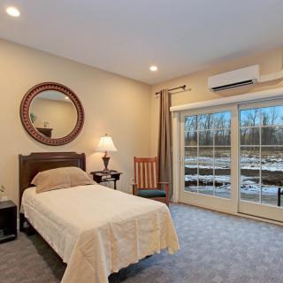 A cozy bedroom with a single bed, decorative mirror, and glass doors leading outside.