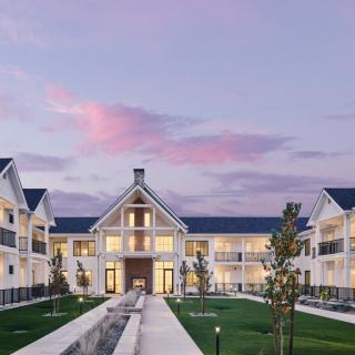 A modern residential building with a beautifully landscaped garden at dusk.