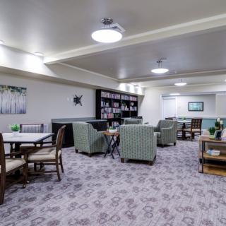 A cozy lounge area with comfortable seating, tables, and bookshelves.