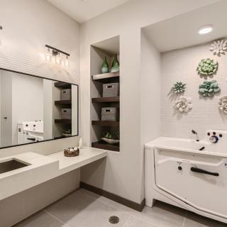 A modern bathroom with sleek fixtures, decorative wall art, and built-in shelving.