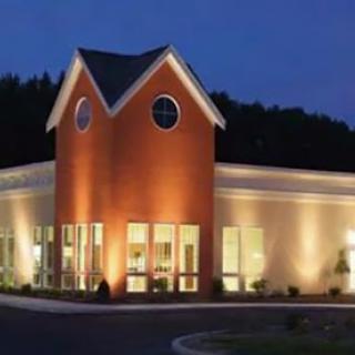 A well-lit modern building at dusk, showcasing its architectural features.