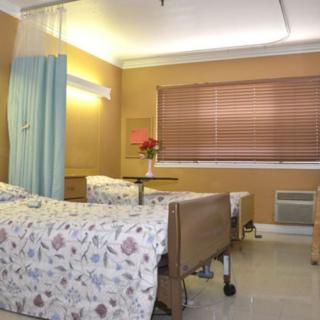 A tidy hospital room with two beds, separated by a curtain and lit by soft lighting.