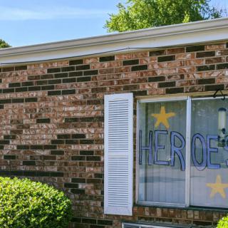 A brick building with a window displaying decorative signs and stars.
