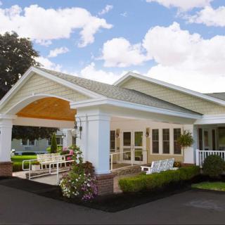 A charming house with a covered porch, surrounded by well-maintained landscaping under a partly cloudy sky.