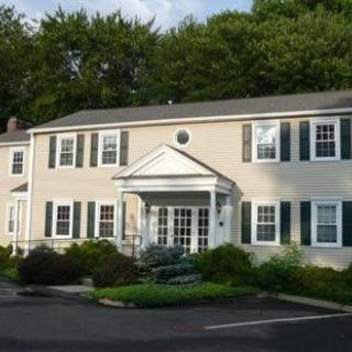 A colonial-style house with green shutters and a well-maintained landscape.