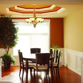 A well-lit dining room with a wooden table and chairs, featuring a chandelier and natural light from the window.