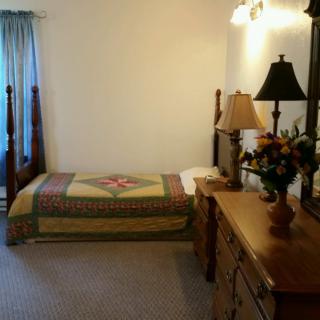 A neat bedroom with a single bed, dresser, and decorative lamp.