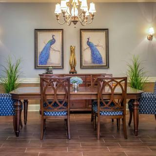 A beautifully decorated dining room featuring elegant wooden furniture, framed artwork, and a chandelier.