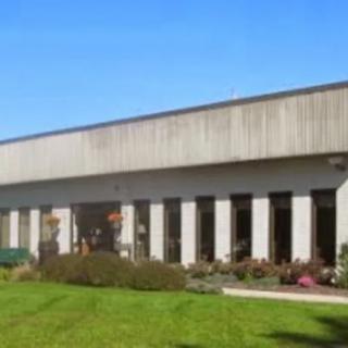 A modern building with a row of columns and a well-kept grassy area in the foreground.