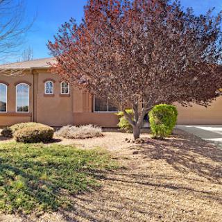 A cozy residential house surrounded by a well-maintained front yard and a beautiful tree.