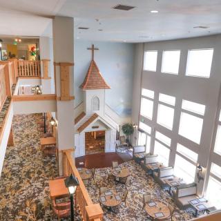 A spacious interior featuring a small chapel-like structure, large windows, and seating arrangements.