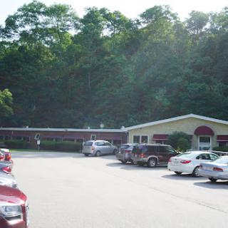 A view of a building surrounded by a parking lot and greenery.