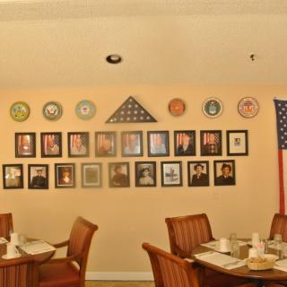 A dining area adorned with military memorabilia, including framed photos and an American flag.