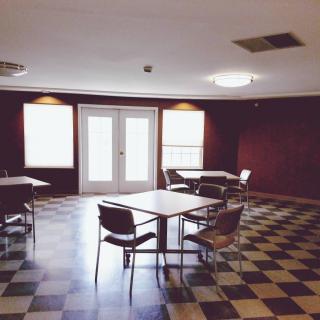 An empty room with checkered flooring, tables, and chairs.
